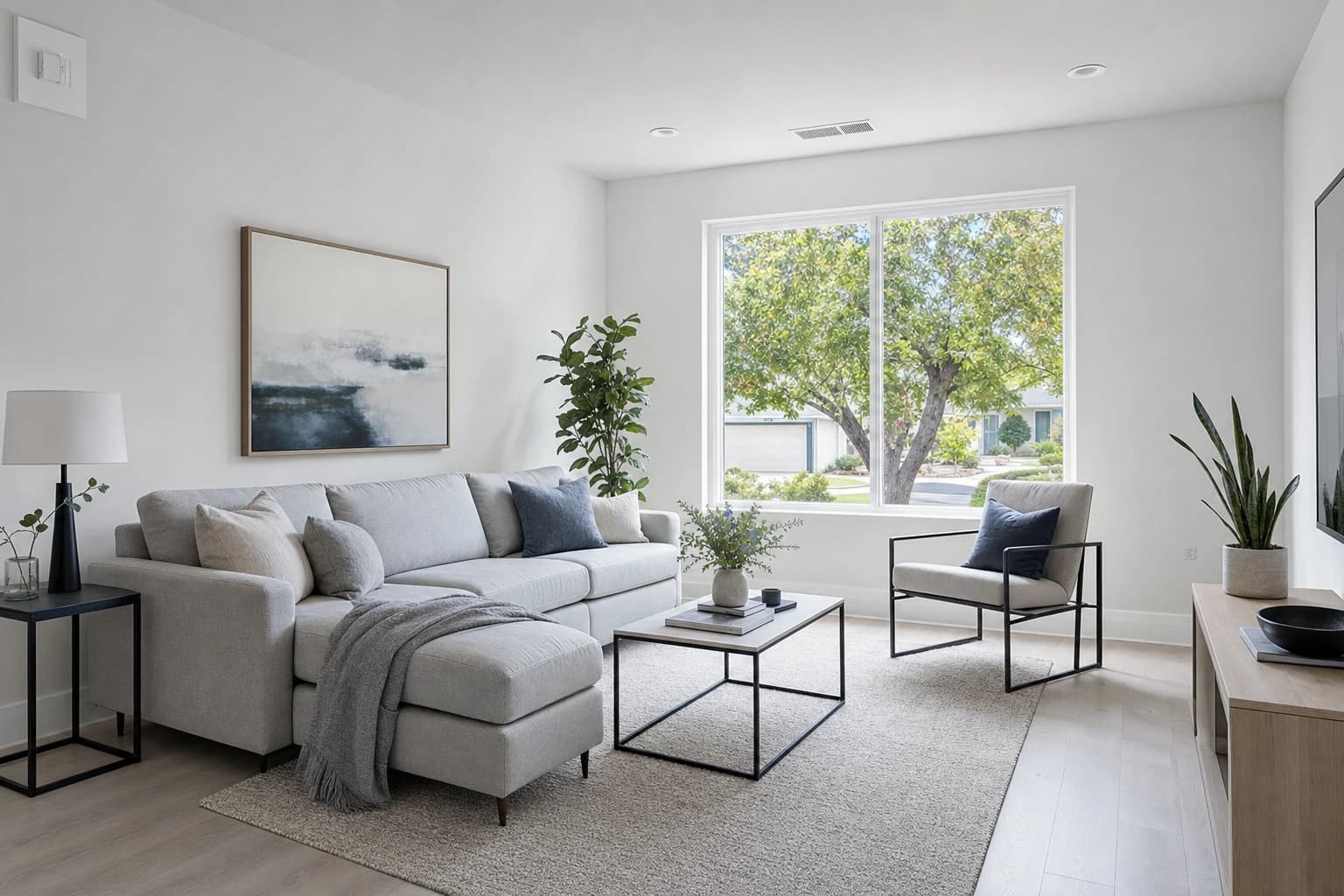 Bright Sacramento living room with grey LVP floors and leafy greenery outside the window