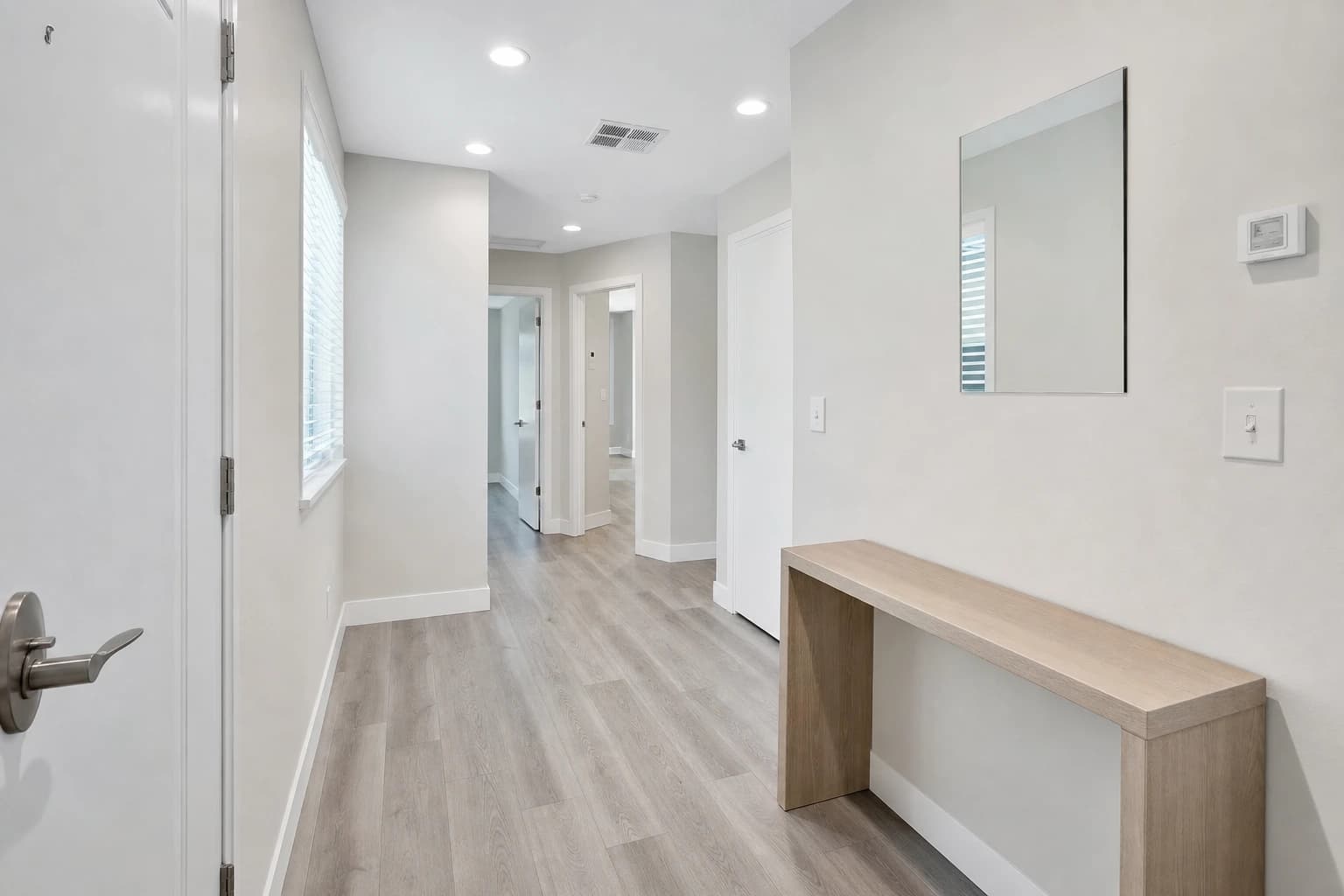 Plain entry and hallway with grey LVP floors and white doors in a Rancho Cordova home remodel